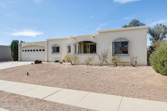 view of front of house with concrete driveway, an attached garage, and stucco siding