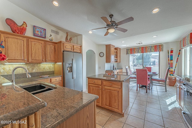 kitchen featuring tasteful backsplash, lofted ceiling, sink, light tile patterned floors, and stainless steel refrigerator with ice dispenser