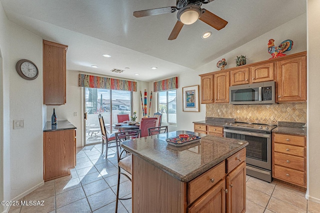 kitchen featuring lofted ceiling, a kitchen bar, tasteful backsplash, a center island, and stainless steel appliances