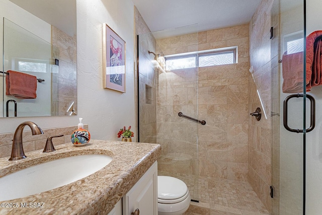 bathroom with vanity, a shower with door, and toilet