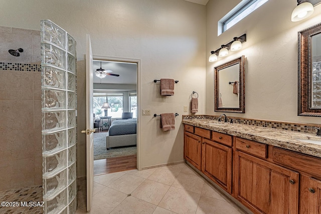 bathroom with a healthy amount of sunlight, tile patterned flooring, vanity, and a tile shower