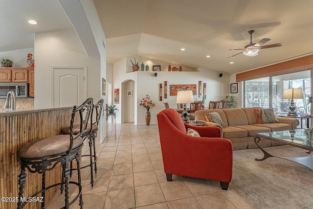 living room with vaulted ceiling, sink, light tile patterned floors, and ceiling fan