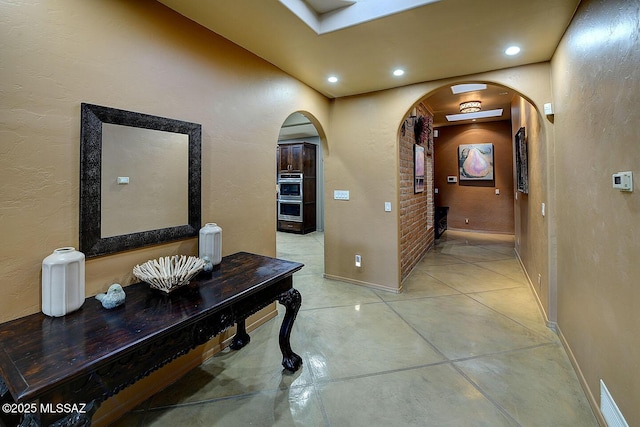 corridor featuring arched walkways, baseboards, and recessed lighting