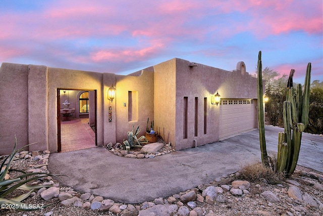 view of front facade featuring concrete driveway, an attached garage, and stucco siding