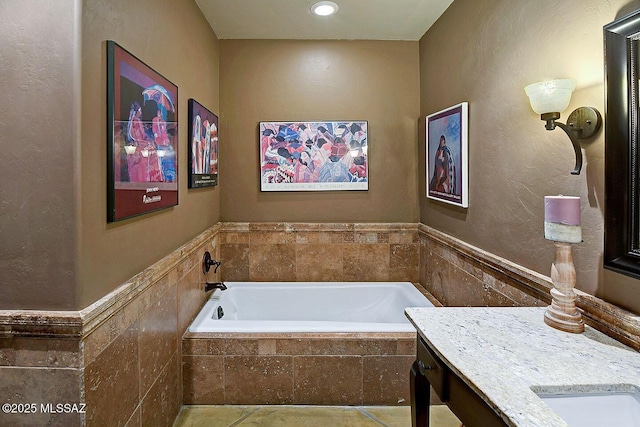 full bath featuring a garden tub, a wainscoted wall, and vanity