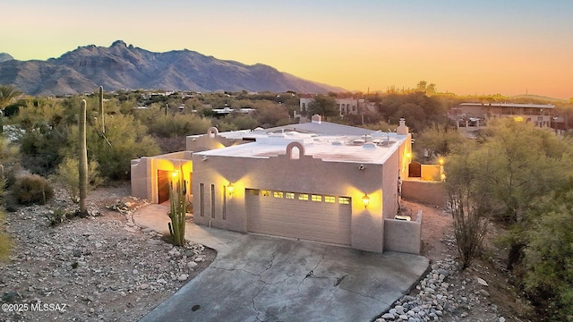 southwest-style home featuring driveway, a mountain view, and stucco siding