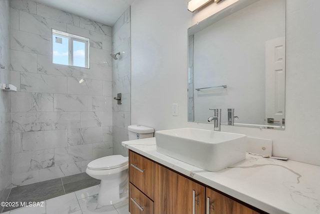 bathroom with vanity, toilet, and a tile shower