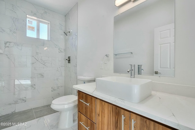 bathroom with tiled shower, vanity, and toilet