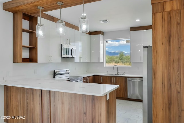 kitchen with decorative light fixtures, white cabinetry, sink, kitchen peninsula, and stainless steel appliances