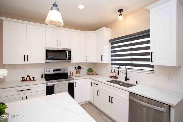 kitchen featuring appliances with stainless steel finishes, decorative light fixtures, sink, and white cabinets