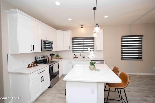 kitchen featuring a breakfast bar, sink, white cabinetry, a kitchen island, and stainless steel appliances