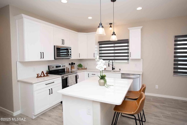 kitchen featuring sink, appliances with stainless steel finishes, white cabinetry, a center island, and decorative backsplash