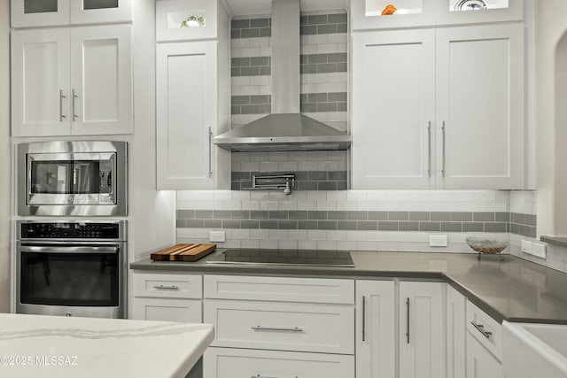 kitchen with white cabinetry, black electric cooktop, and wall chimney range hood