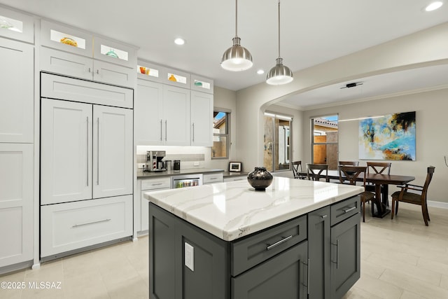 kitchen featuring decorative light fixtures, light stone countertops, and white cabinets