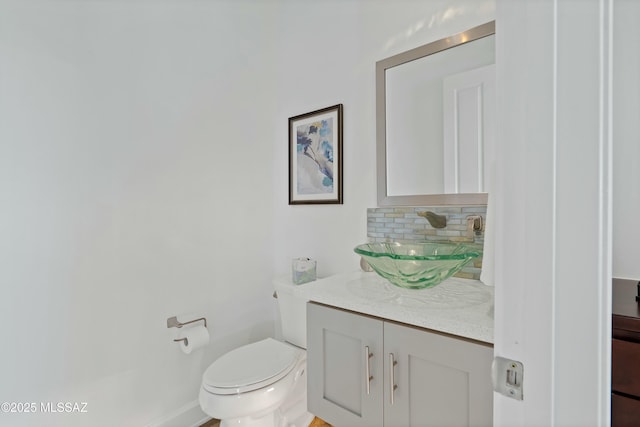 bathroom featuring vanity, backsplash, and toilet