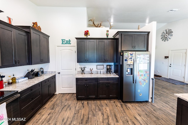 kitchen with hardwood / wood-style flooring, stainless steel fridge, dark brown cabinets, and range with electric stovetop