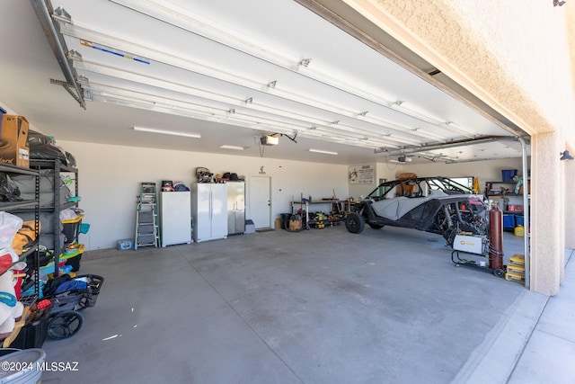 garage with a garage door opener and white fridge