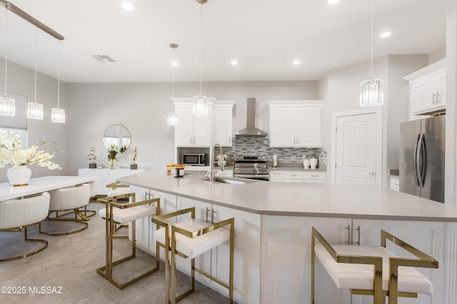 kitchen with wall chimney exhaust hood, a breakfast bar, sink, decorative light fixtures, and stainless steel appliances