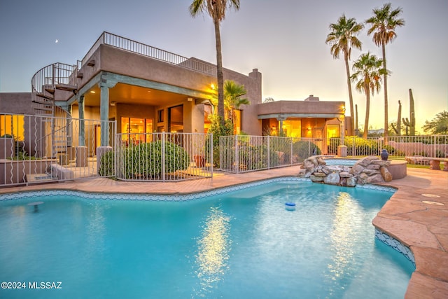 pool at dusk featuring an in ground hot tub and a patio