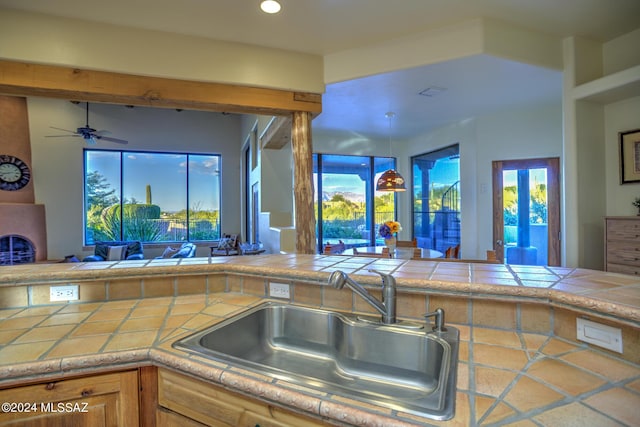 kitchen with tile counters, sink, and a wealth of natural light