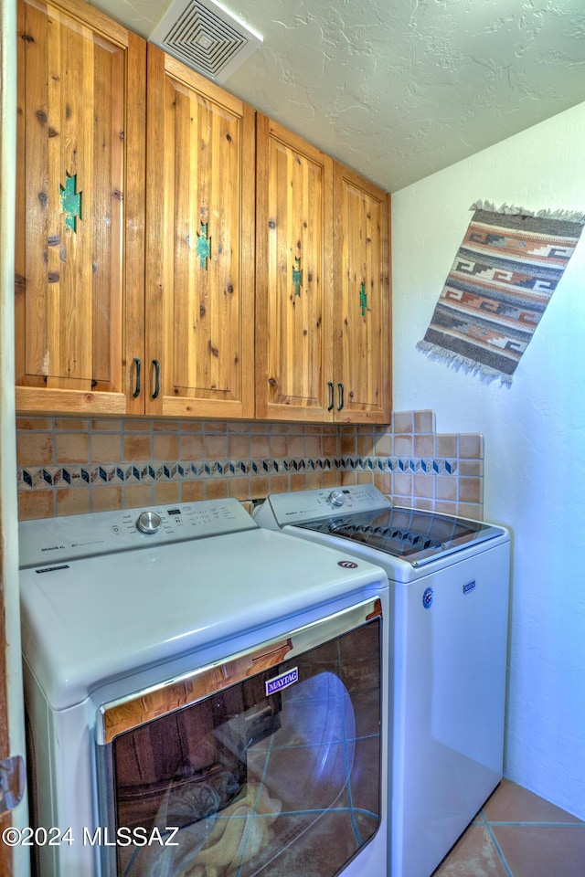 laundry area featuring cabinets, washer and dryer, light tile patterned floors, and a textured ceiling