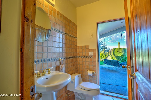 bathroom with tile walls, sink, and toilet