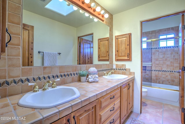 full bathroom with a skylight, decorative backsplash, enclosed tub / shower combo, vanity, and toilet