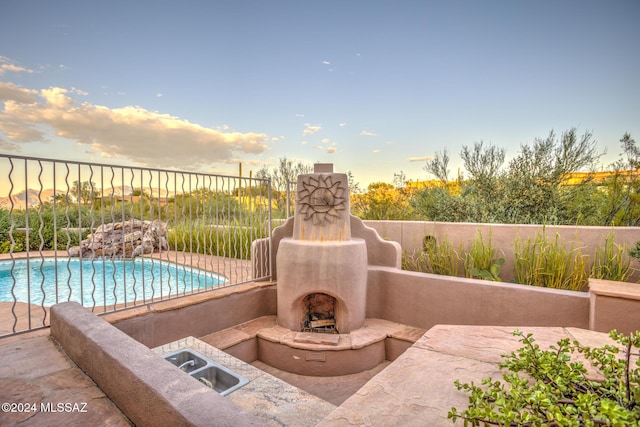 view of patio / terrace with exterior fireplace and a fenced in pool