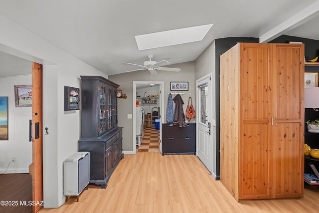 interior space featuring lofted ceiling with skylight, washer / dryer, and light wood-type flooring