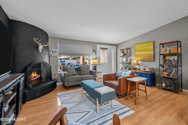 living room with light hardwood / wood-style flooring, a fireplace, and vaulted ceiling