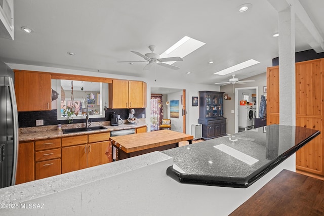 kitchen with washer / dryer, sink, a skylight, a center island, and dishwasher