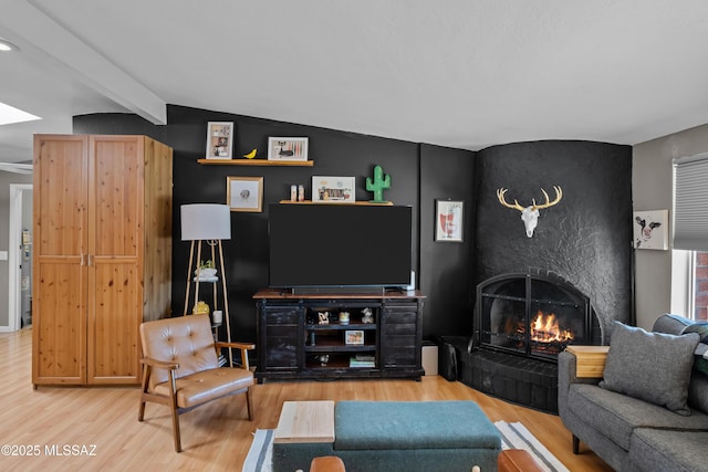 living room with lofted ceiling with beams, a large fireplace, and hardwood / wood-style floors