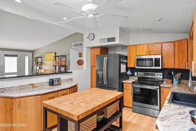 kitchen with stainless steel appliances, vaulted ceiling, sink, and kitchen peninsula