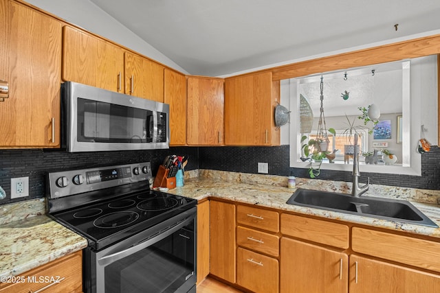 kitchen with sink, appliances with stainless steel finishes, light stone counters, tasteful backsplash, and vaulted ceiling