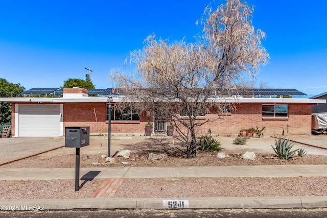 ranch-style house featuring a garage and solar panels