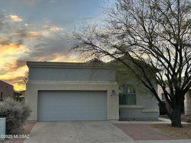 view of front facade featuring an attached garage, concrete driveway, and stucco siding