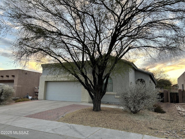 view of front facade featuring a garage, decorative driveway, and stucco siding