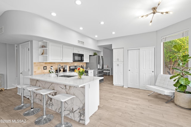 kitchen featuring sink, appliances with stainless steel finishes, a kitchen breakfast bar, white cabinets, and kitchen peninsula