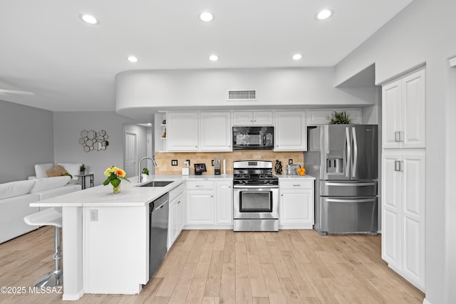 kitchen featuring a breakfast bar, sink, white cabinetry, kitchen peninsula, and black appliances