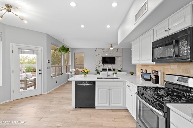 kitchen with white cabinetry, kitchen peninsula, sink, and black appliances