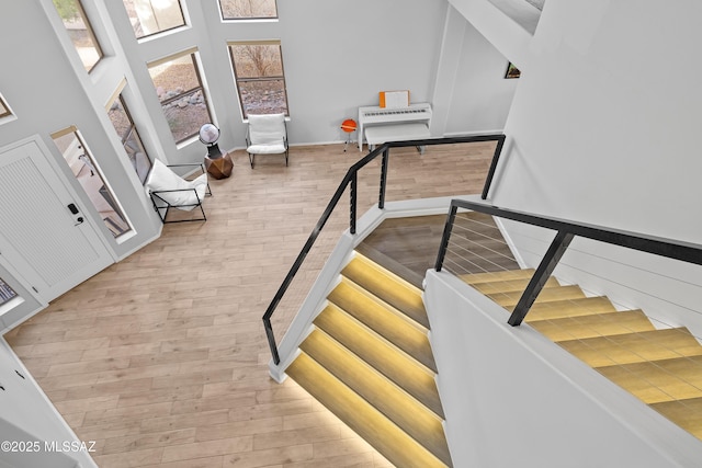 stairs with hardwood / wood-style floors and a towering ceiling