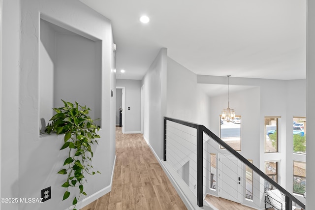 hallway featuring an inviting chandelier and light hardwood / wood-style floors