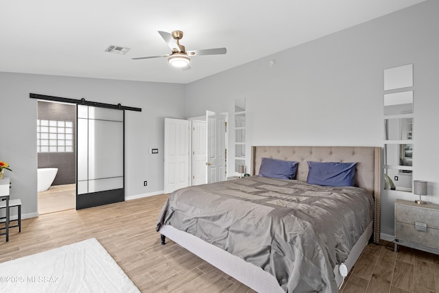 bedroom with lofted ceiling, a barn door, ceiling fan, and light wood-type flooring