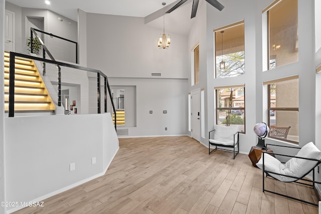 foyer entrance with wood-type flooring, high vaulted ceiling, and a chandelier