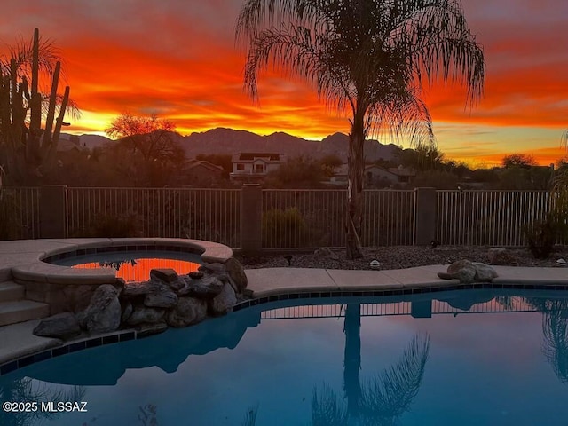 pool at dusk with an in ground hot tub and a mountain view