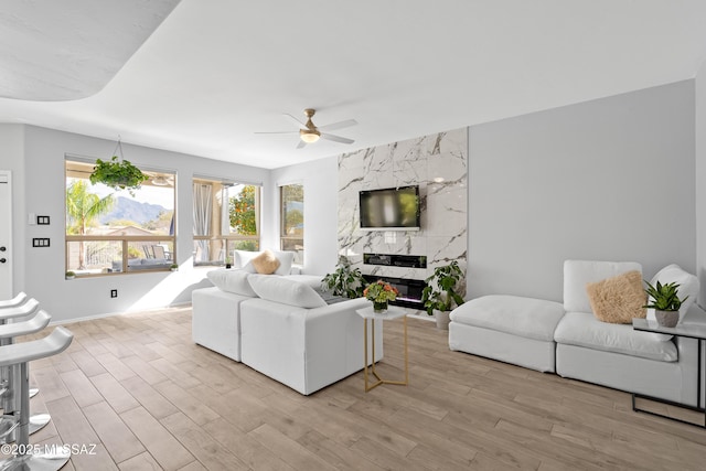 living room featuring a fireplace, ceiling fan, and light hardwood / wood-style flooring