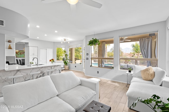 living room featuring ceiling fan, sink, and light hardwood / wood-style flooring