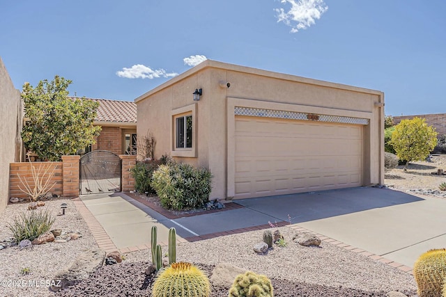 adobe home featuring stucco siding, a tiled roof, concrete driveway, and a gate