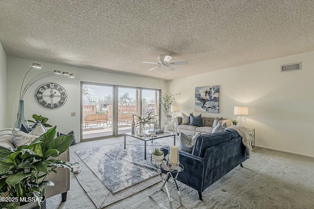 living area featuring visible vents, a ceiling fan, a textured ceiling, carpet flooring, and baseboards