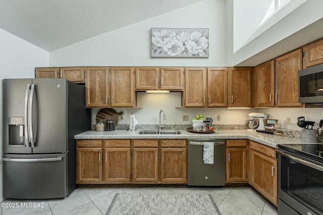 kitchen with a sink, stainless steel appliances, brown cabinetry, and light countertops